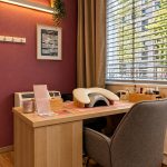 Poste de manucure avec lampe et repose-main près d’une fenêtre à stores, institut de beauté à Genève