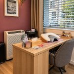 Bureau de manucure avec cadre mural, flacons de vernis et fauteuil gris dans un institut à Genève