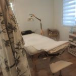 Salle de soin avec table de massage et lampe chauffante du cabinet Médecine chinoise Est-Ouest à Métabief